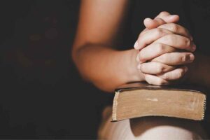 A woman sitting with a Bible in her hands, deep in prayer