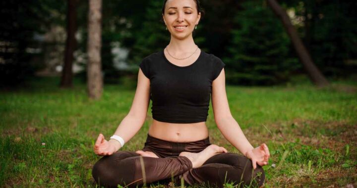 Person meditating outdoors in a peaceful setting surrounded by nature.