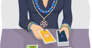 Image of a tarot reader at a table laying out tarot cards, wearing a pentagram necklace.