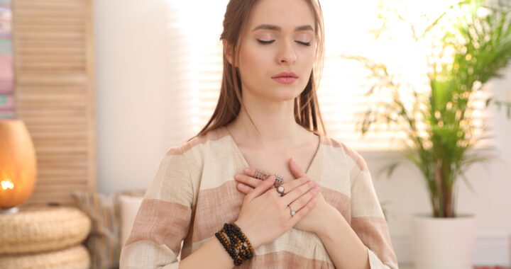 The self-healing course logo features a woman with her eyes closed in meditation toucing her heart center in a peaceful room with a salt lamp, plant, and natural lighting.