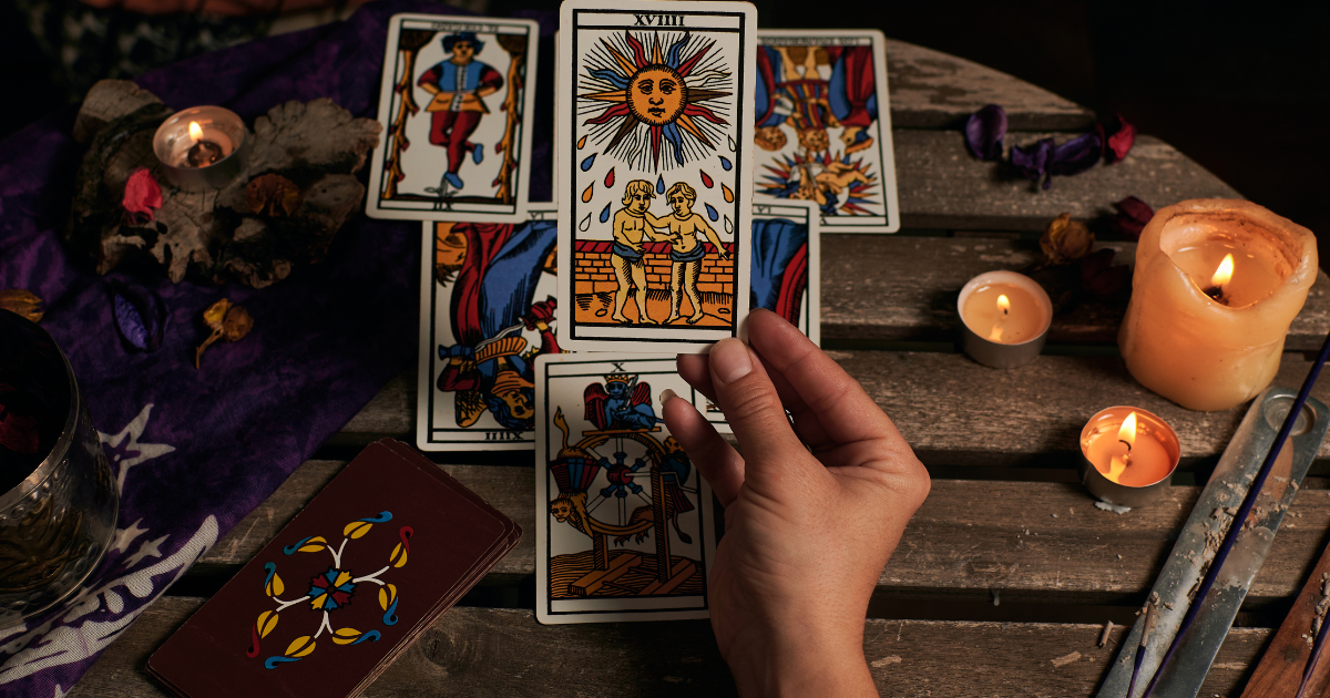 A person dealing out tarot cards on a wood table.