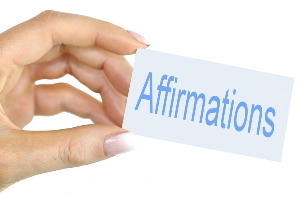 A hand holding a slip of paper that says affirmations. This is intended to represent the 2nd of 6 spiritual practices meant to enhance your intuition.